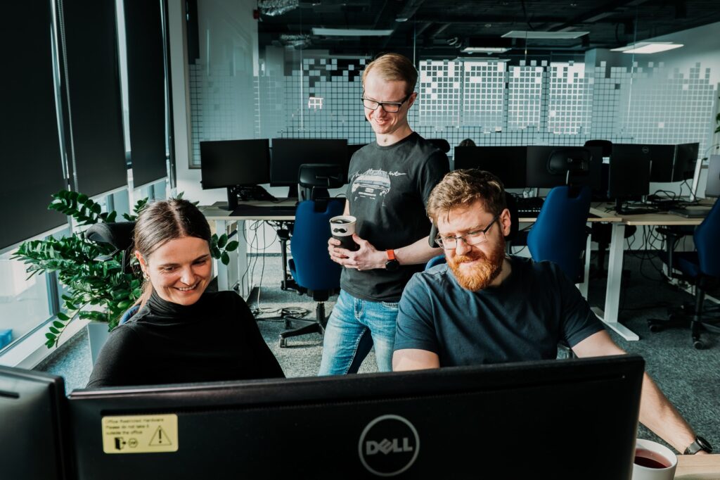 Pracownicy Spyrosoft przed komputerem w biurze na open spejsie