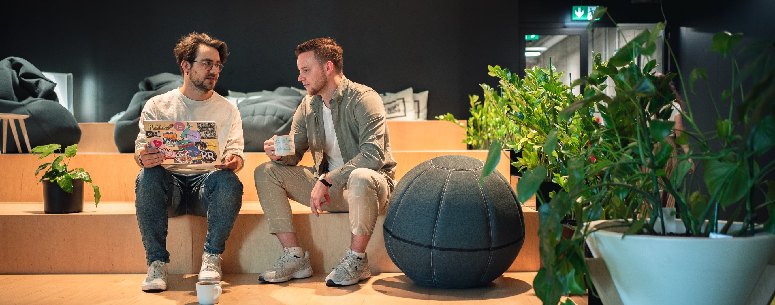 Dwóch pracowników firmy Spyrosoft rozmawia ze sobą na open spejsie w biurze